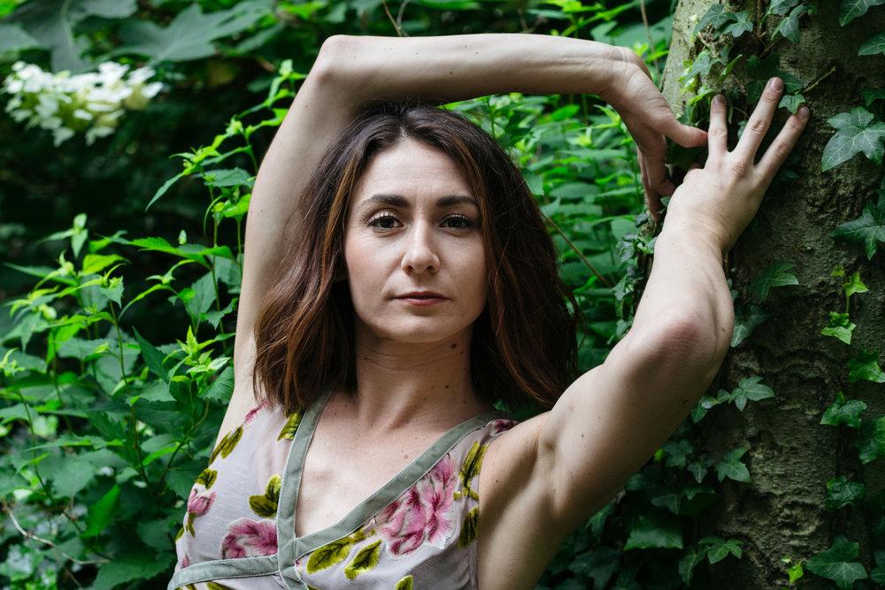 Woman standing near wall of foliage